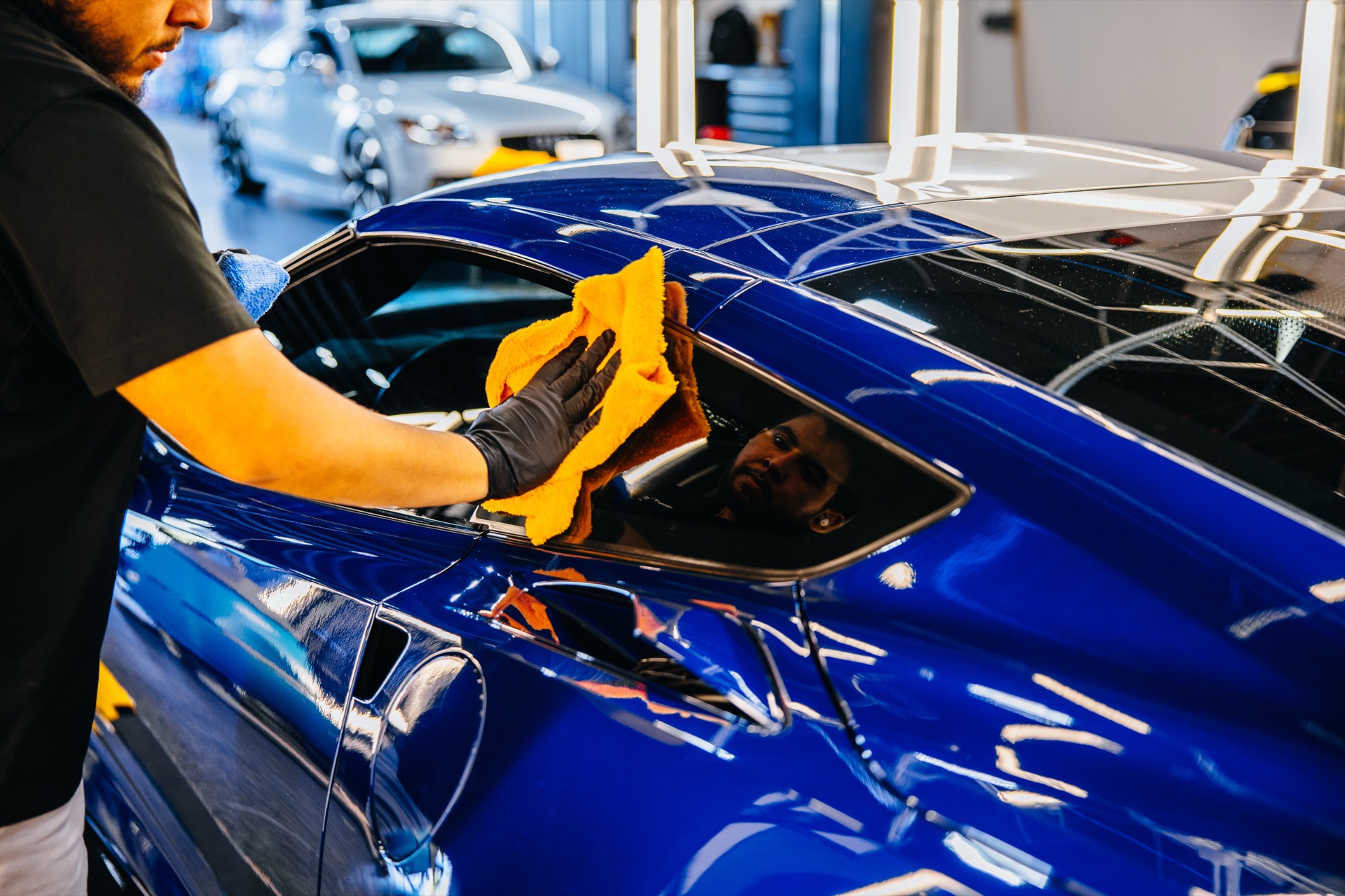 Technician wiping down a blue Corvette after ceramic coating at Pristine Film Solutions